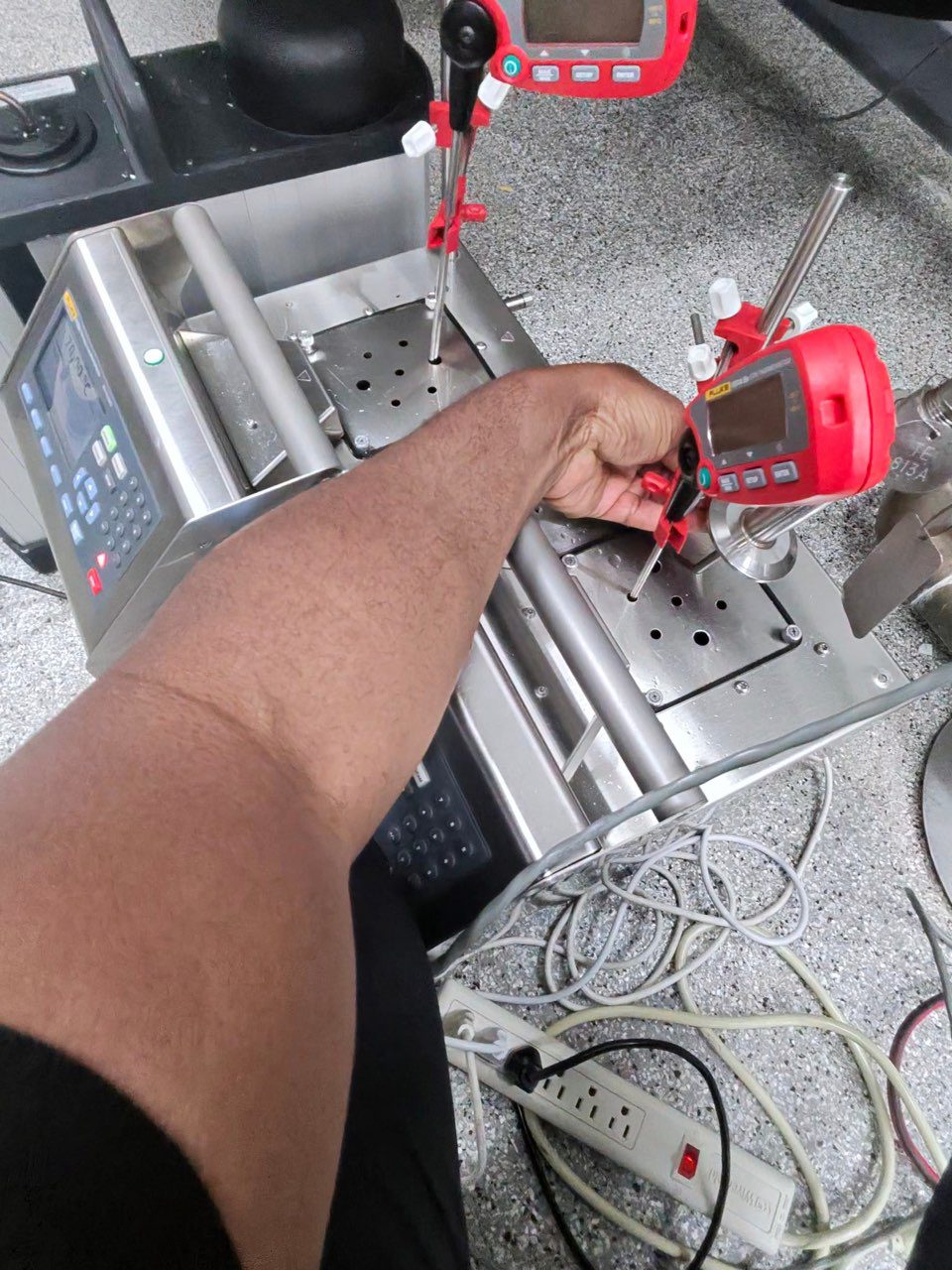 Arm adjusting red digital gauges on metal fixture